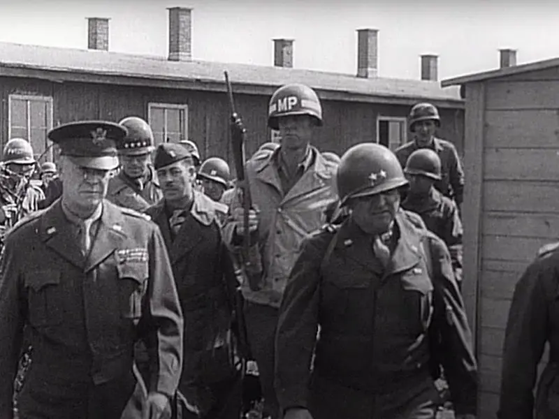 General Eisenhower and U.S. soldiers entering the Ohrdruf concentration camp at the end of World War II, where he was shocked by the atrocities and urged U.S. leaders and journalists to witness the genocide firsthand and inform the world.
